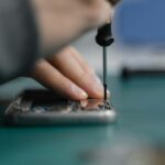 Detailed shot of smartphone repair with a screwdriver and hand close-up.